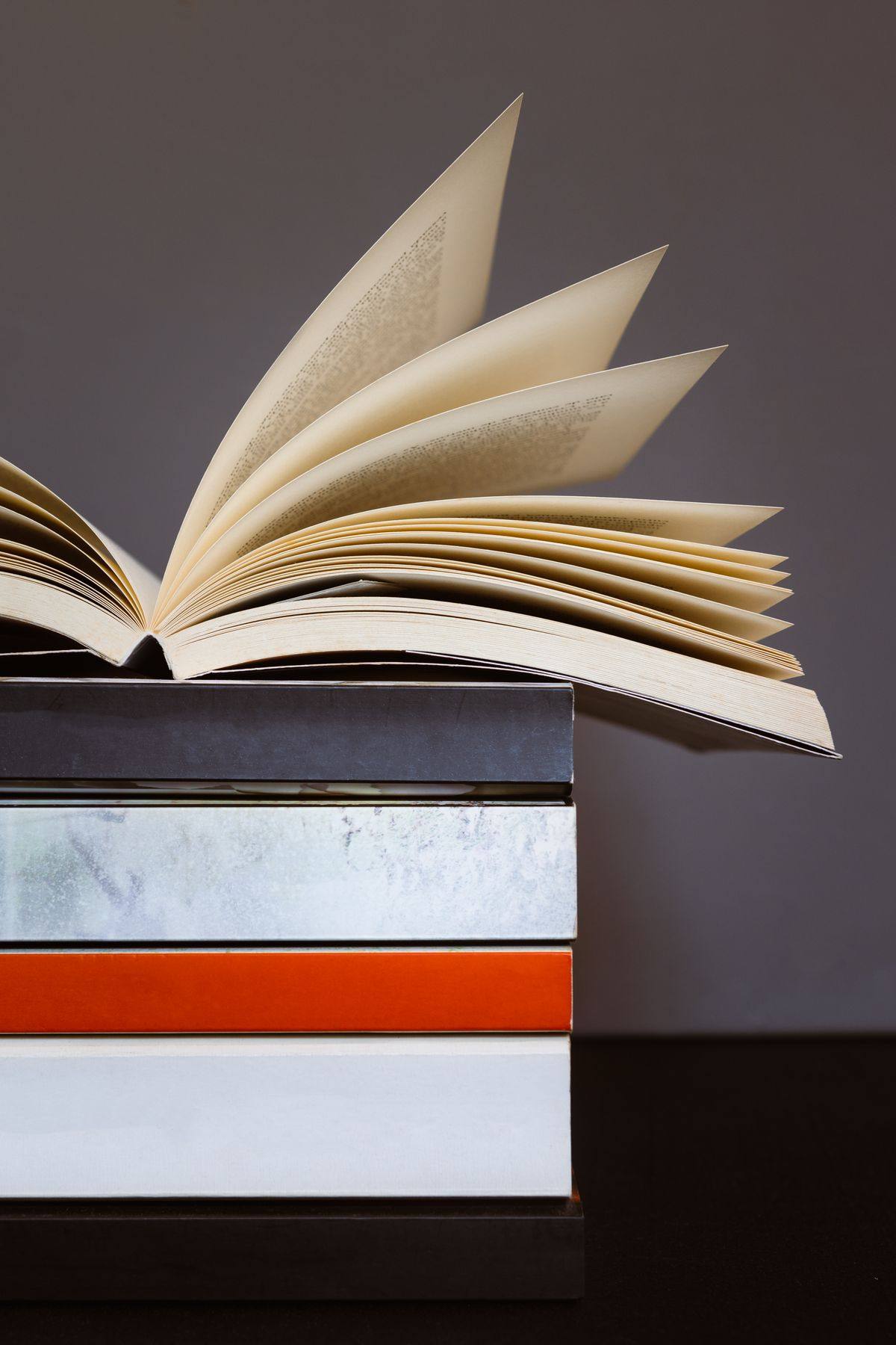 Buku terbuka di atas tumpukan buku bacaan